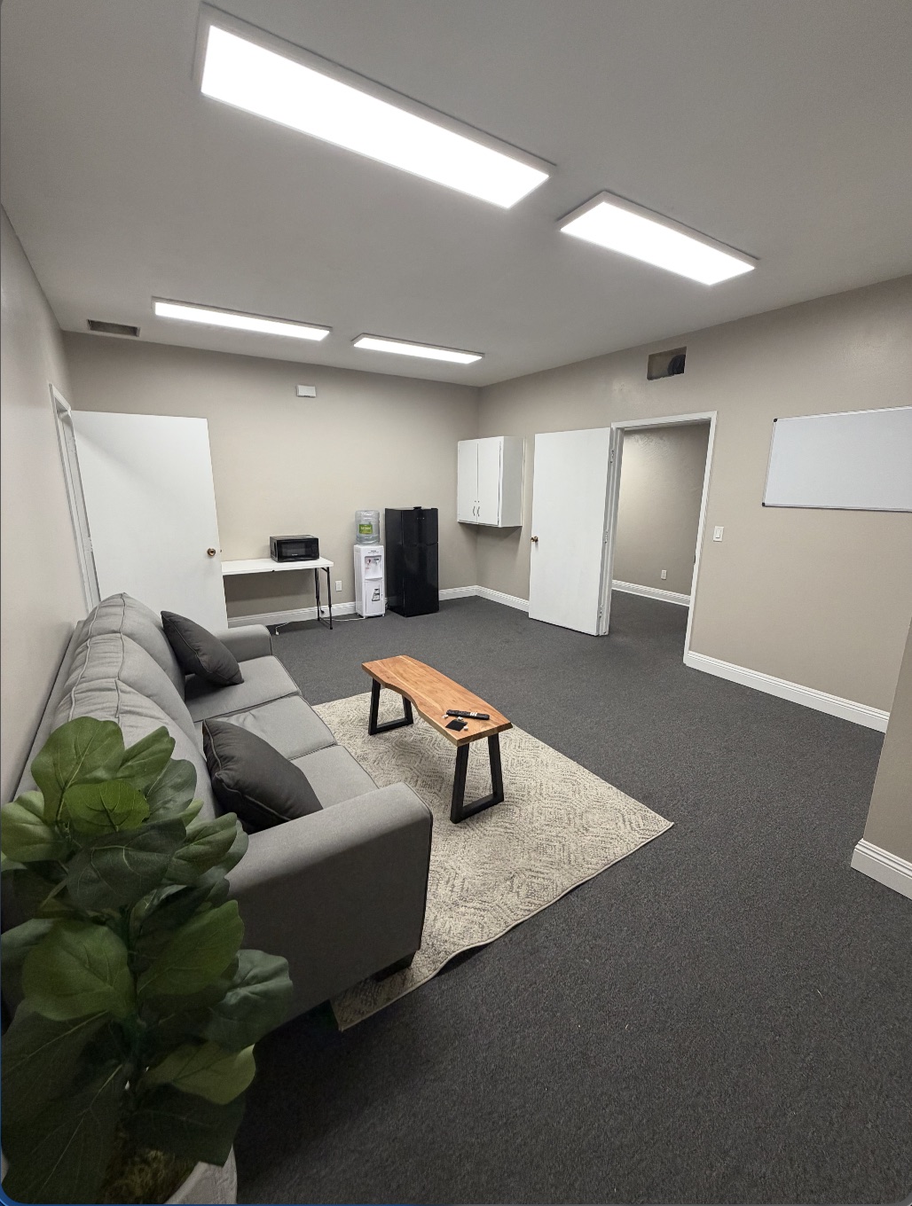 Client lounge at Golden Coast Rehab with sectional couch, coffee table, and refreshment area